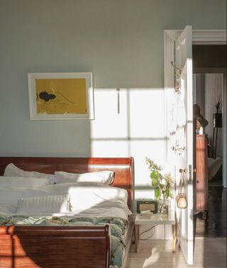 Farrow and Ball pale green bedroom walls with wood bed frame