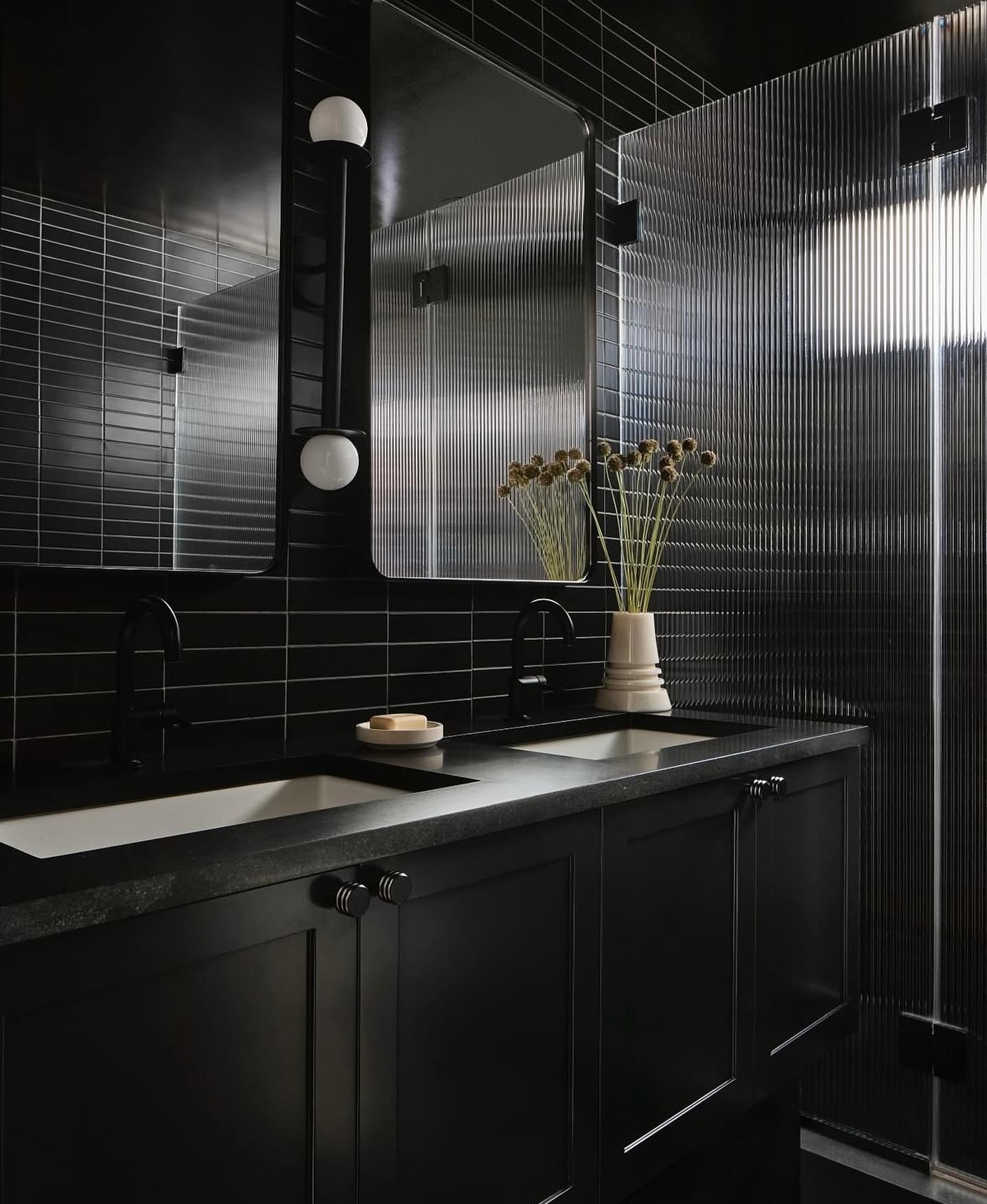 Image of an all-black modern bathroom with black cabinetry and black tiles on the walls.