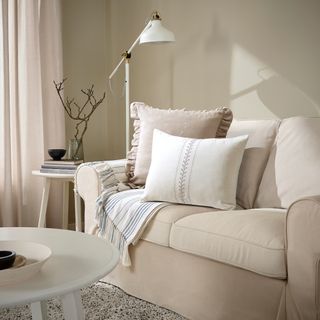 ÅKERNEJLIKA Cushion cover in off white on a beige armchair in a living room