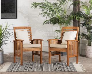 Walker Edison Rendezvous Modern 2 Piece Solid Acacia Wood Slat Back Outdoor Dining Chairs on patio sitting on black and white rug around plants