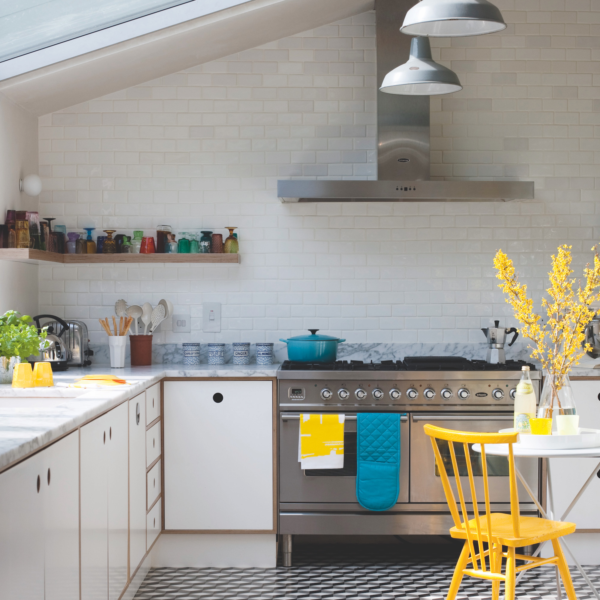 steel range cooker and hood in white kitchen with yellow chair