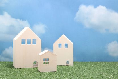 Wooden houses on green grass over blue sky and clouds