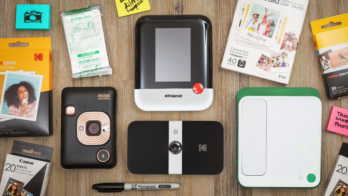 A selection of digital instant cameras, film and paper, arranged on a wooden surface