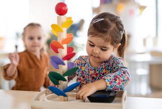 young child playing with wooden toy at nursery