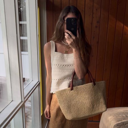 Angie wears a grey t-shirt, cream jumper, blue jeans