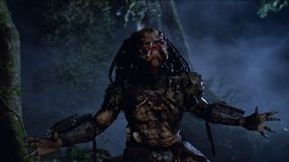 Still from the movie Predator. Here we see Predator without most of their armor, throwing their head and arms back in a battle cry.