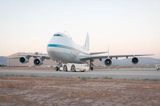 NASA 911, one of two retired Shuttle Carrier Aircraft that ferried NASA's space shuttles across the country for three decades, is towed from NASA Armstrong Flight Research Center's Building 703 on its final journey to the City of Palmdale's nearby Joe Dav