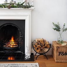 Living room detail of white wall mirror over Edwardian lit fireplace with Christmas decorations