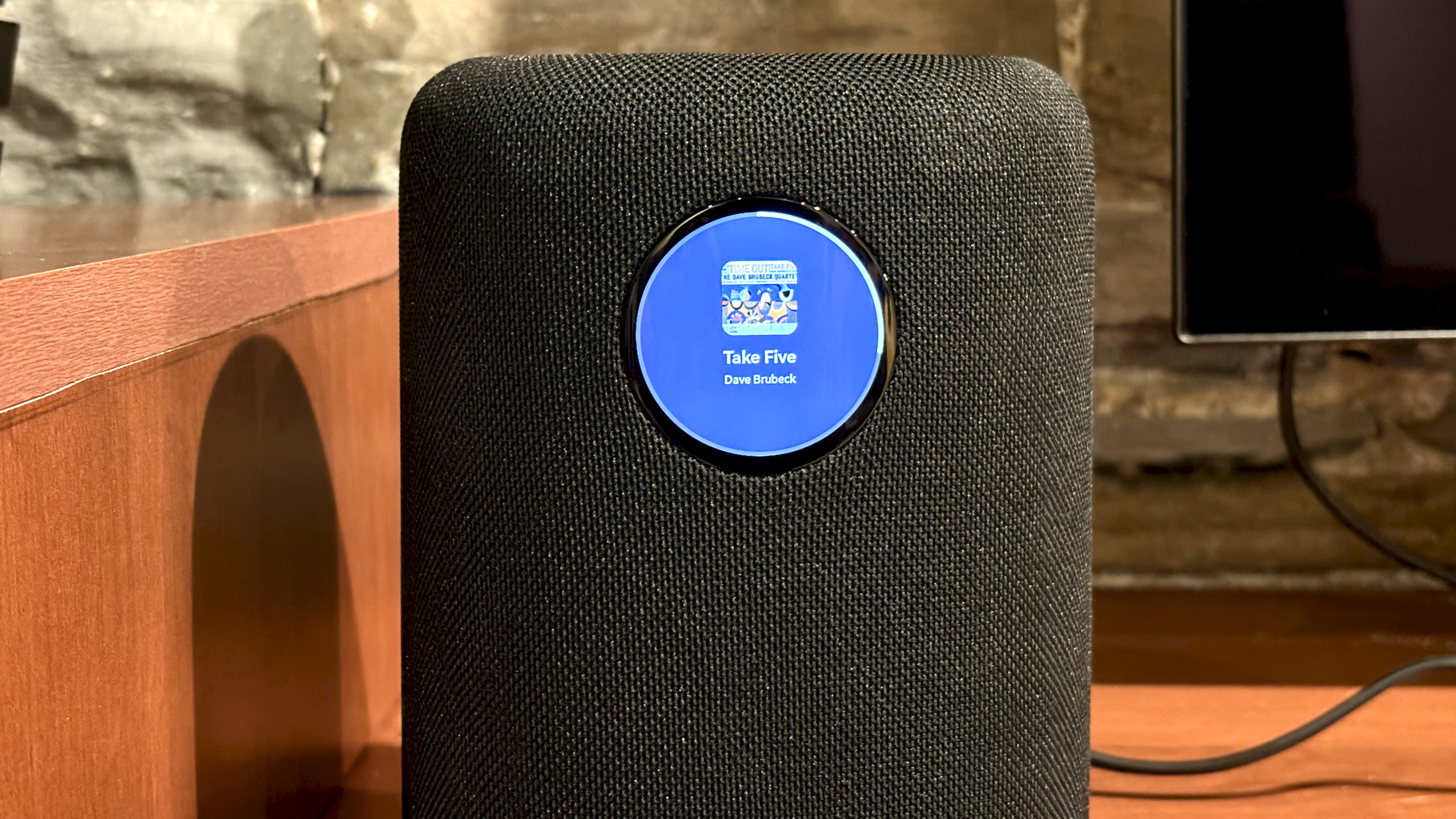 The WiiM Sound, in a home, on a varnished wooden table, showing the illuminated front panel 