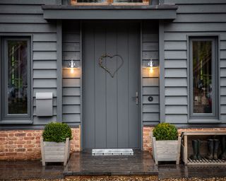 timber canopy porch with grey painted front door and wooden planters