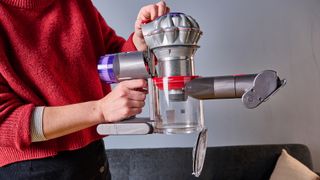 Person showing the bin-empty mechanism on the Dyson Car+Boat handheld vacuum