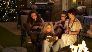Four women from "Orphan Black" sit around in a sitting room, the blonde one, who is front and center, is reading a book