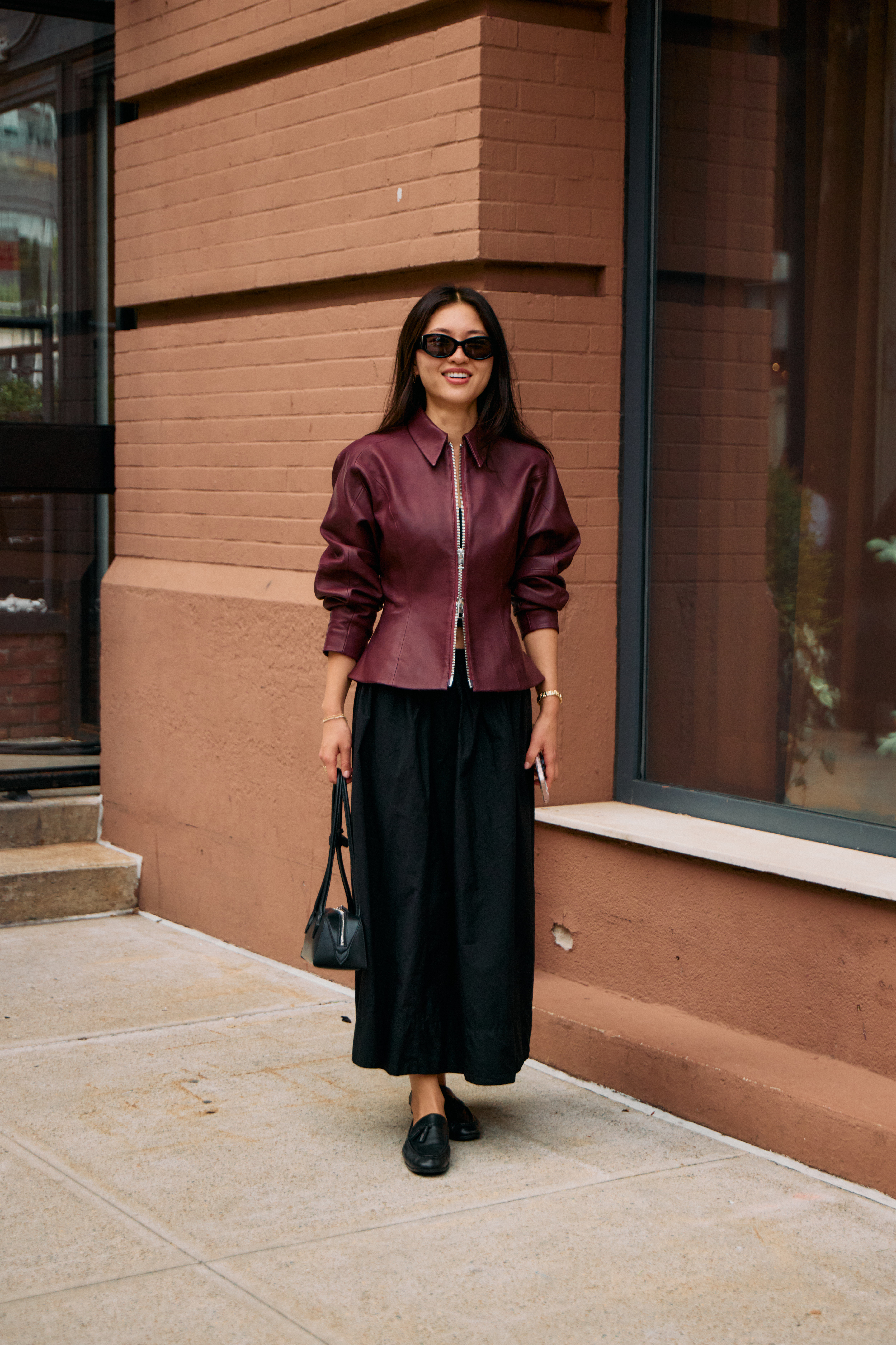 Woman in red leather jacket and black skirt with leather loafers.
