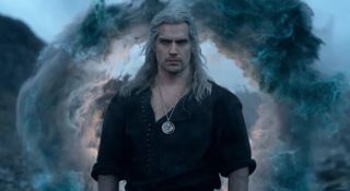 A burly man sporting long white hair with swirling smoke in the background