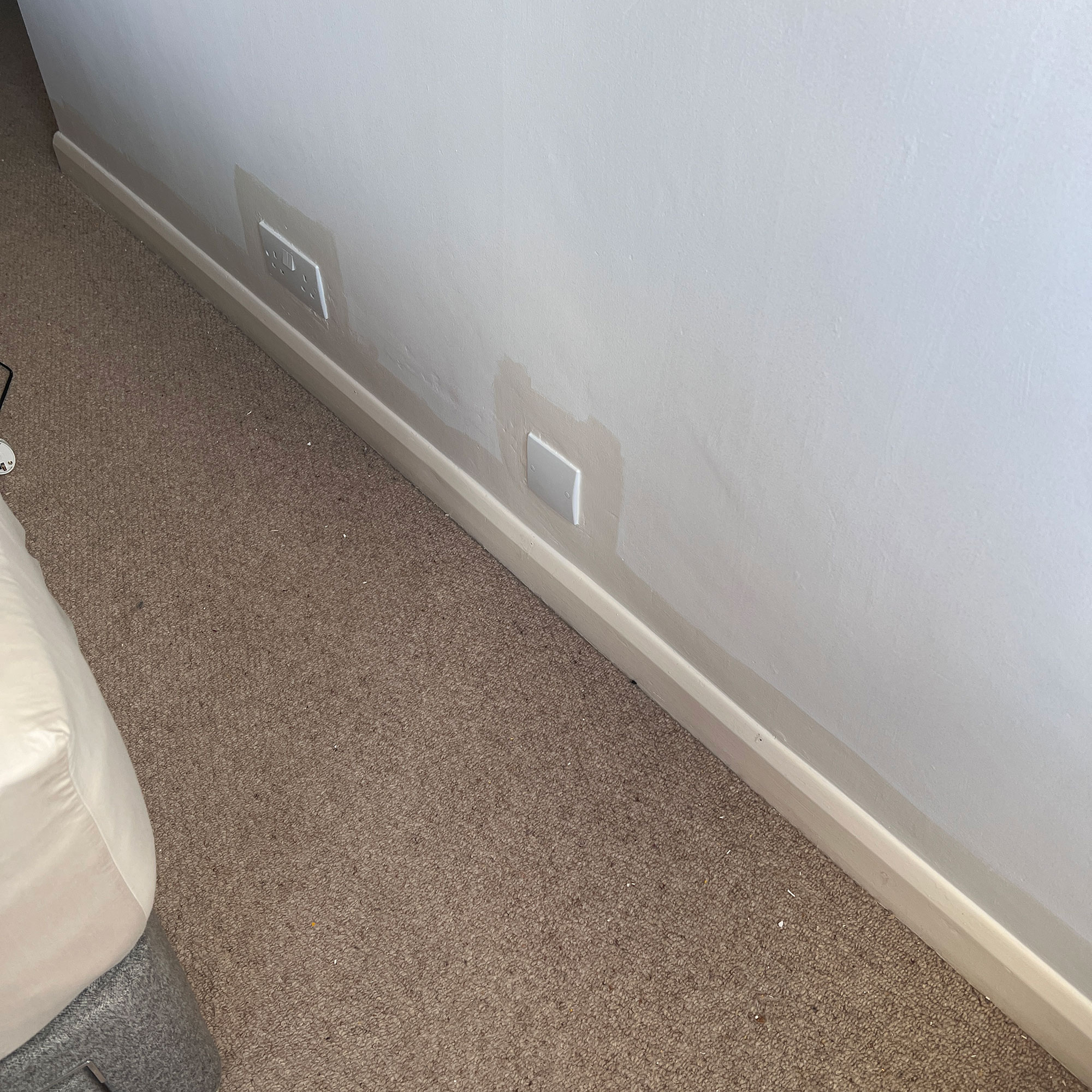 White wall, skirting board and beige carpet