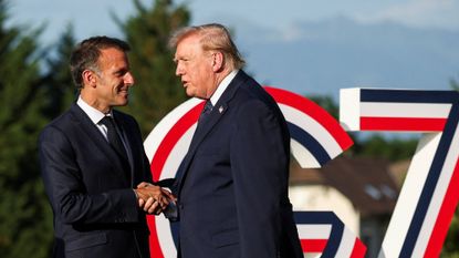 Emmanuel Macron greets Donald Trump in front of a large G7 installation during the G7 Summit at Hotel Royal Evian