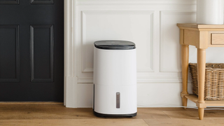 Dehumidifier in front of a panelled wall, a door and wooden table