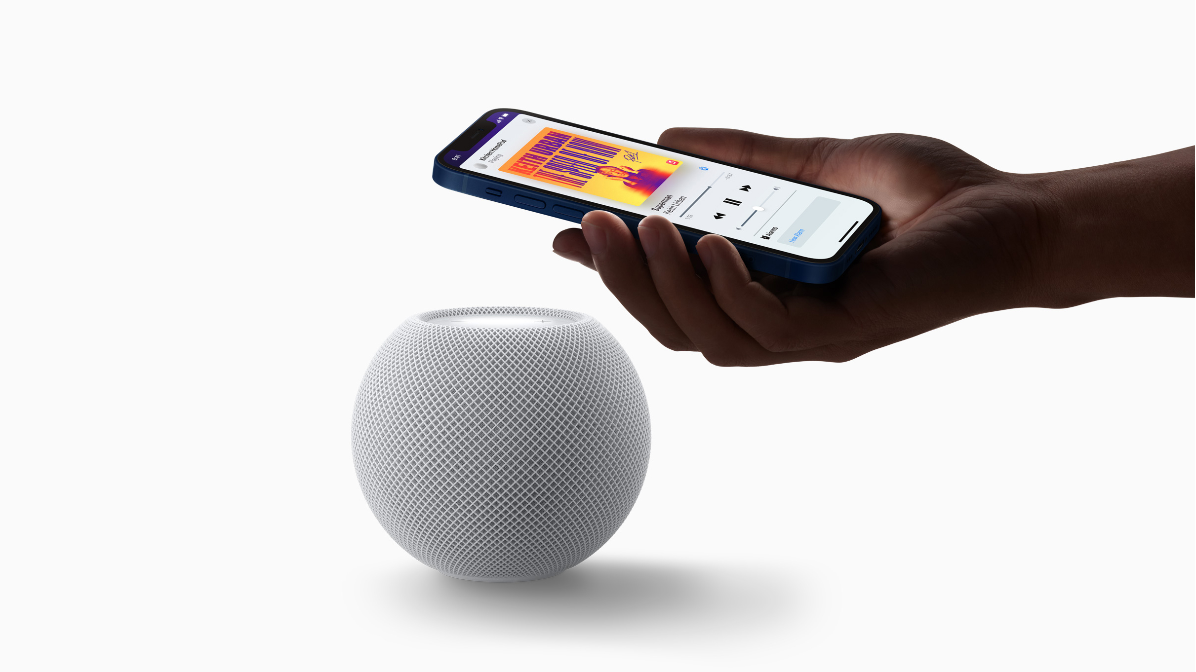 Someone holding an iPhone displaying Apple Music above an Apple HomePod smart speaker.