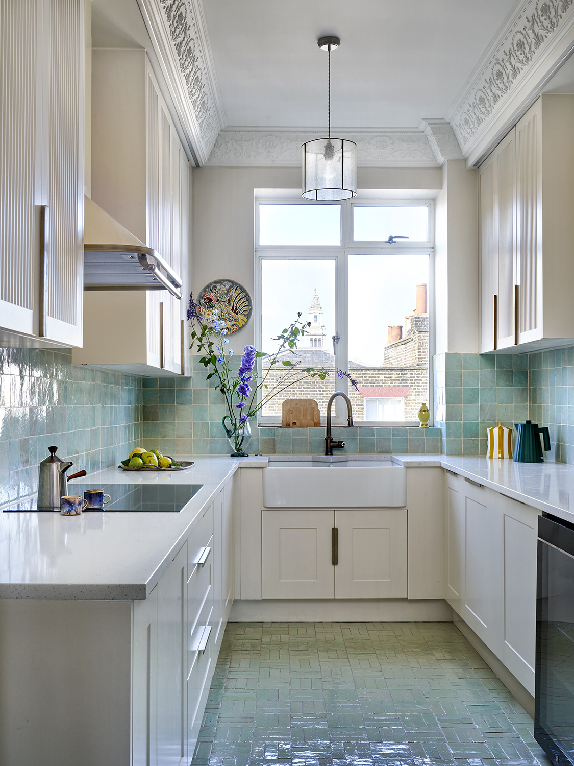 a small galley kitchen with crown molding and blue zellige tiles on the wall and floor