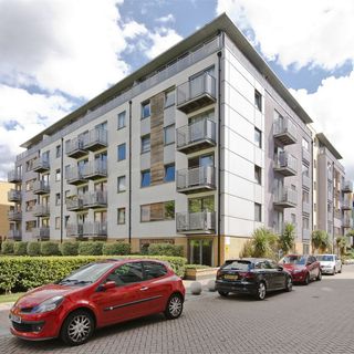 white building with balconies cars and plants