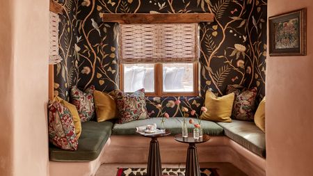 an earthy plaster nook in a Santa Fe adobe home with moody floral wallpaper and a banquette with olive green cushions