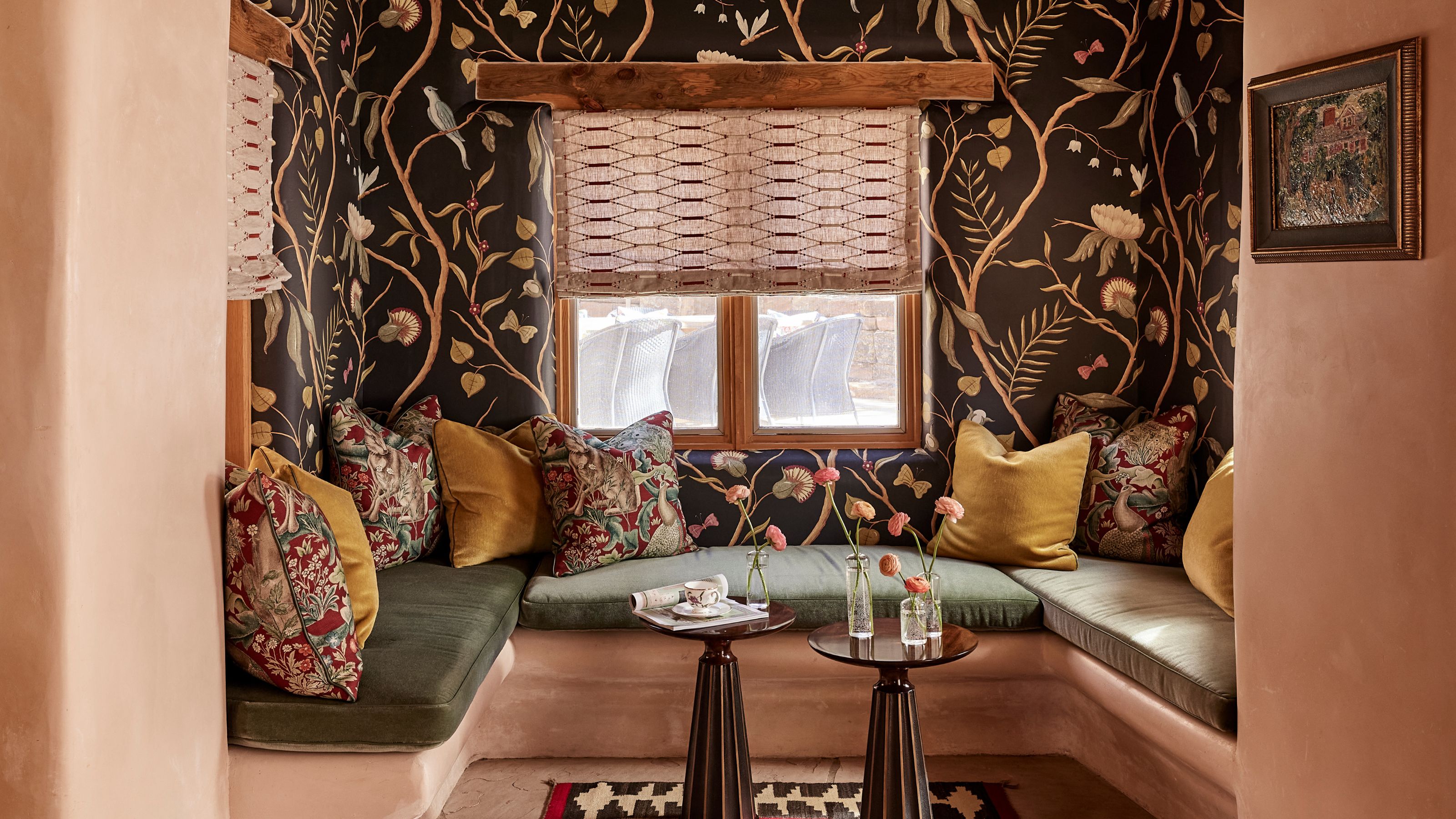 an earthy plaster nook in a Santa Fe adobe home with moody floral wallpaper and a banquette with olive green cushions