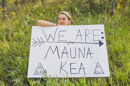 Actress Shailene Woodley holds a sign saying "We are Mauna Kea."