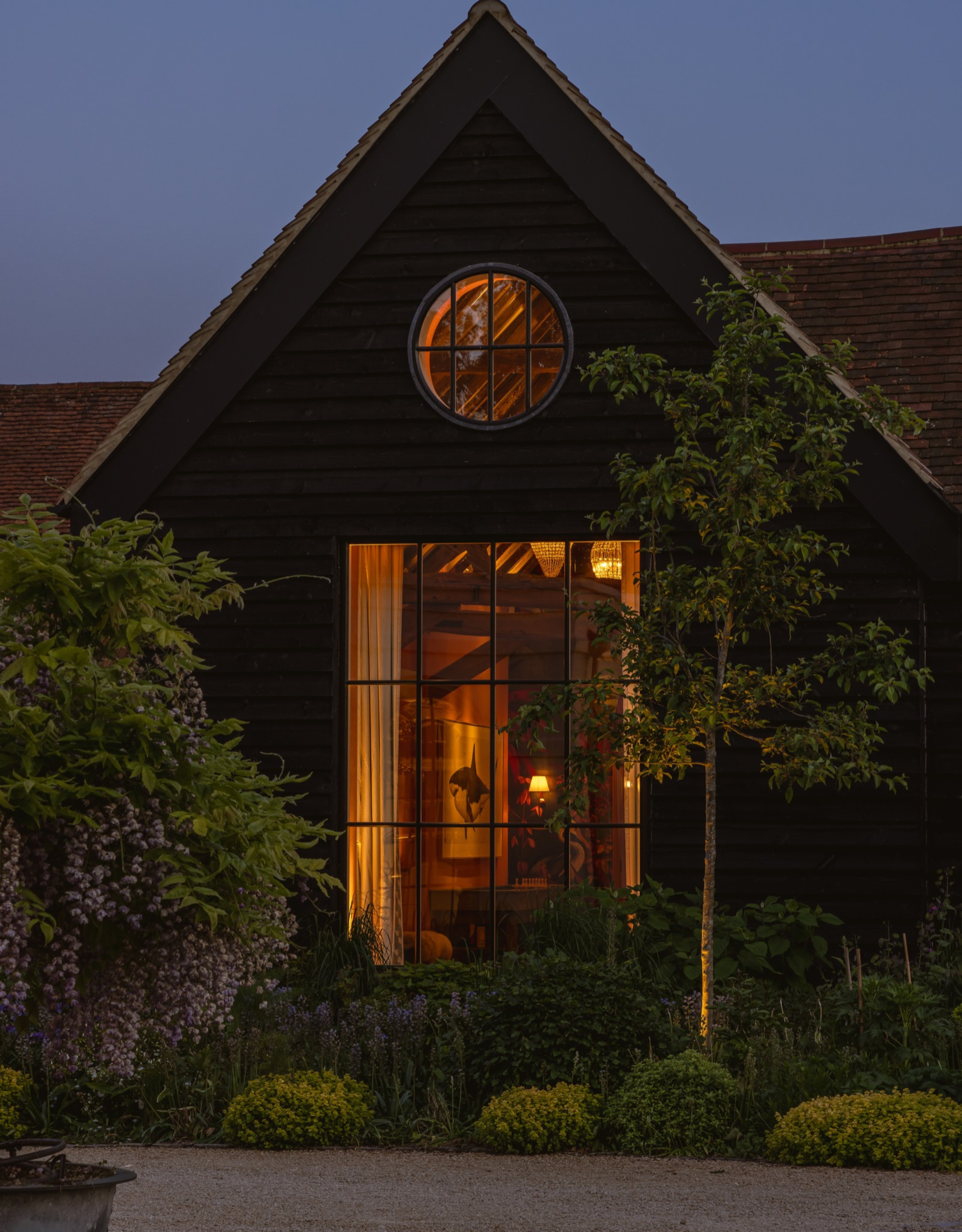 a beautiful country home, shot from outside, with large windows glowing from within