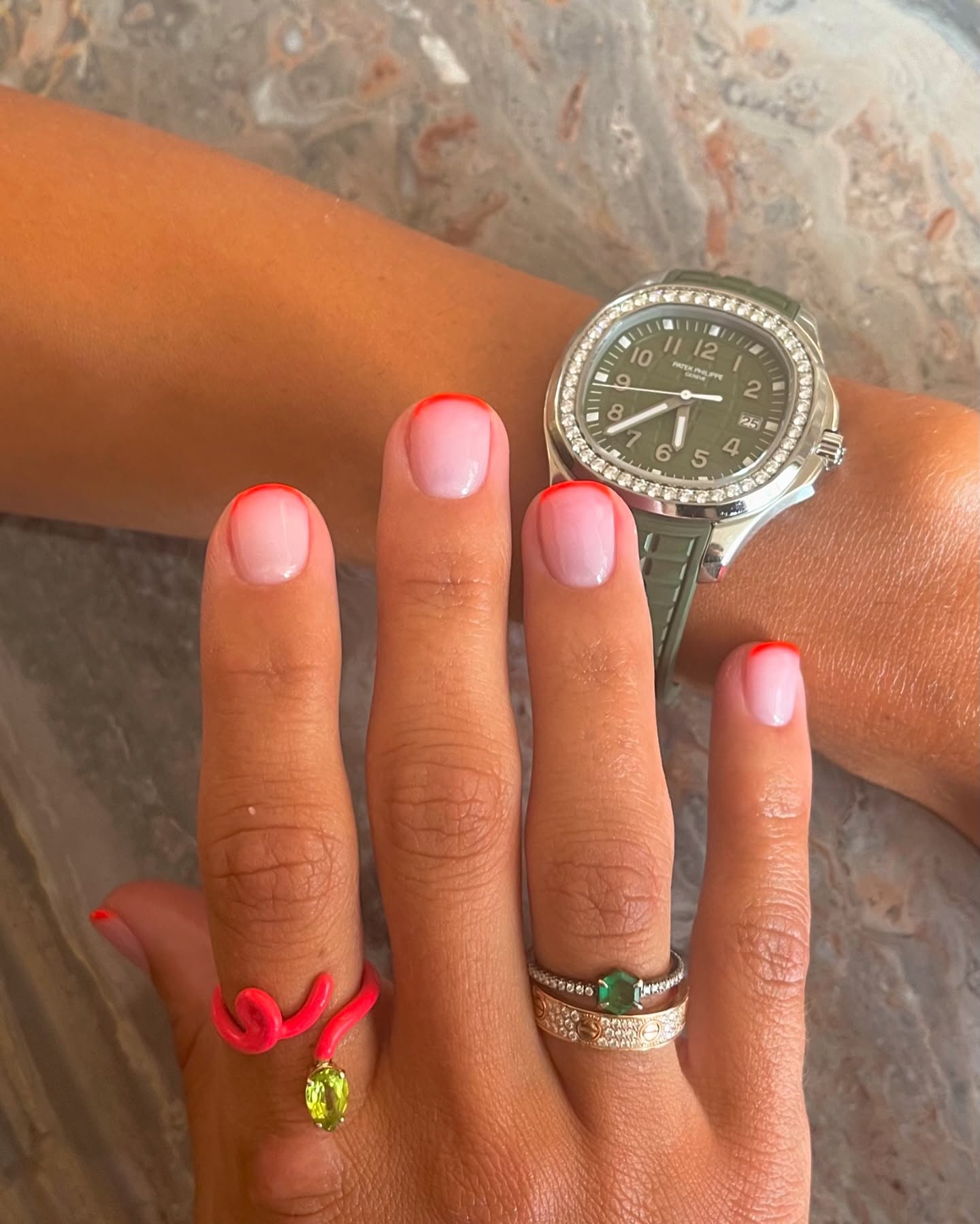 Photo of a woman wearing a neon French manicure and green watch