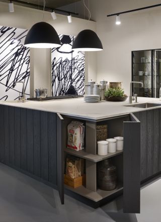 large kitchen island with black wooden sides, corner space, white worktop, black pendants and grey floor