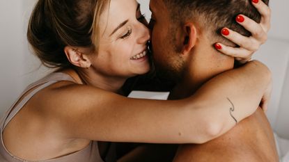 Happy young couple hugging in bed - stock photo