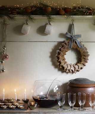 Kitchen Christmas decor ideas with a gingerbread wreath, a bowl of mulled wine and a lit garland