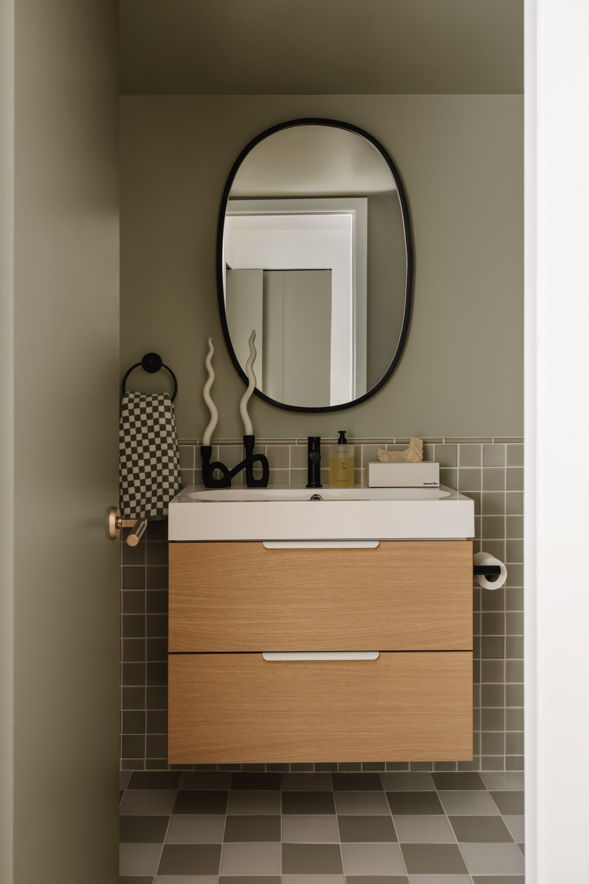 A neutral green color drenched bathroom vanity with square tiles