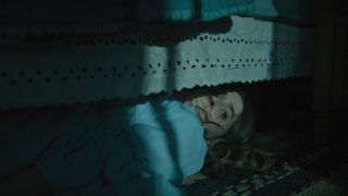 Kaitlyn Dever hides under a bed in No One Will Save You