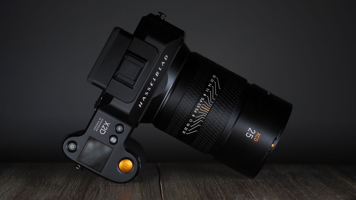 Hasselblad XCD 25V lens, with a Hasselblad X2D camera, on a wooden table, shot with dramatic light against a dark background