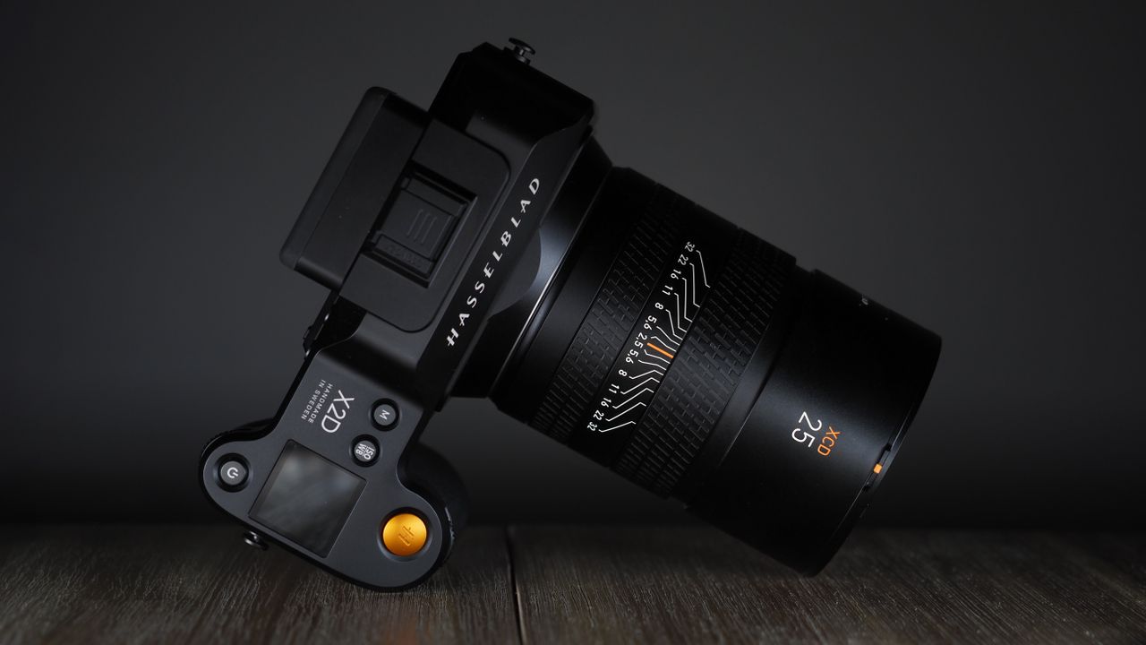 Hasselblad XCD 25V lens, with a Hasselblad X2D camera, on a wooden table, shot with dramatic light against a dark background