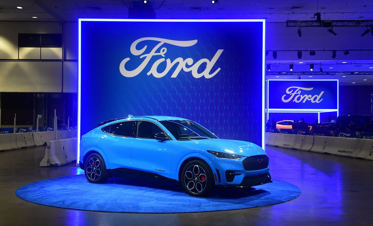 The Ford Mach-E vehicle on display beneath a Ford logo