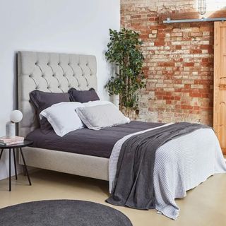 Cream bed frame with grey bedding on top