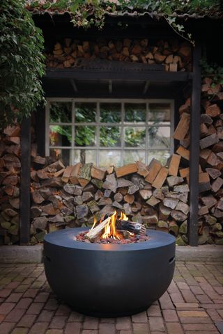 round fire pit in front of log store