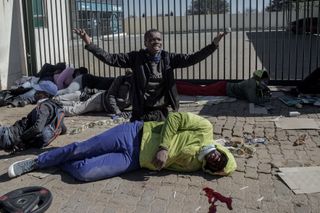 A suspected looter gestures for help after a man was struck by a rubber bullet in Soweto, Johannesburg