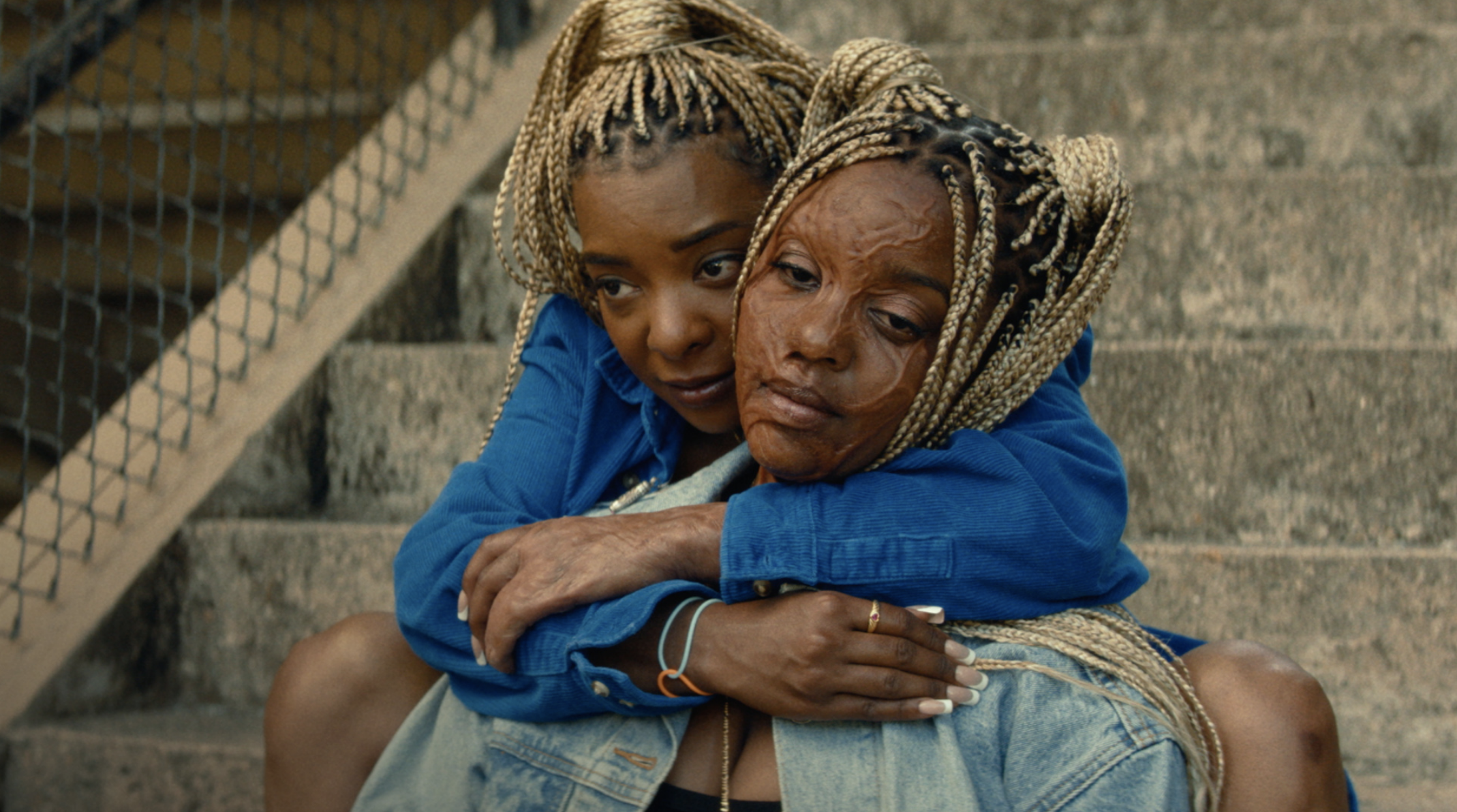 Kara Young embracing Mallori Johnson on a stairwell.