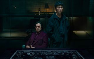 Etsushi Toyokawa and Go Ayano in 'Tokyo Swindlers' standing by a table and looking stern