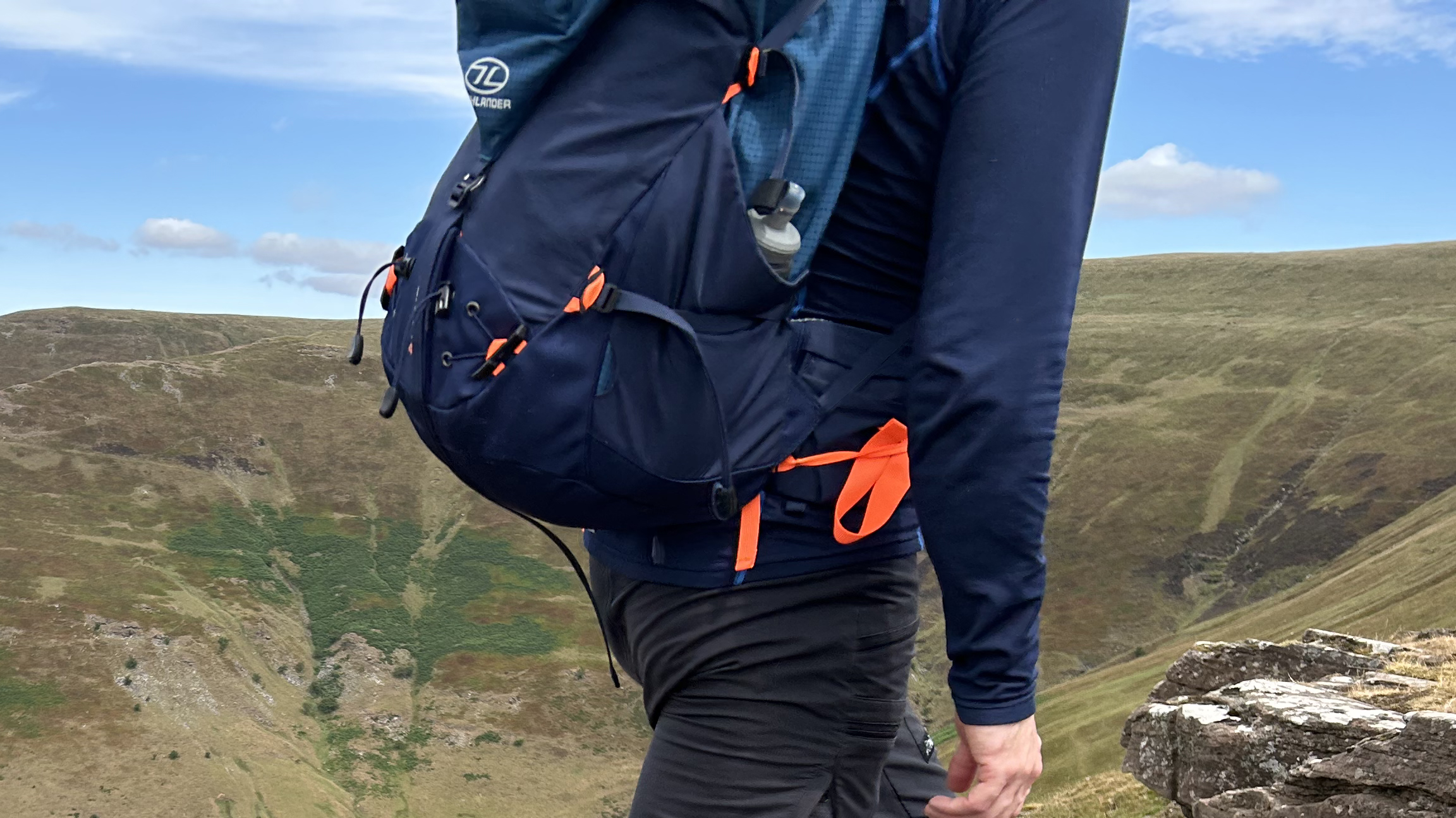 Side profile of a hiker wearing the Highlander Vulkan backpack in the hills
