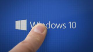 A finger pressing on a screen that reads 'Windows 10'