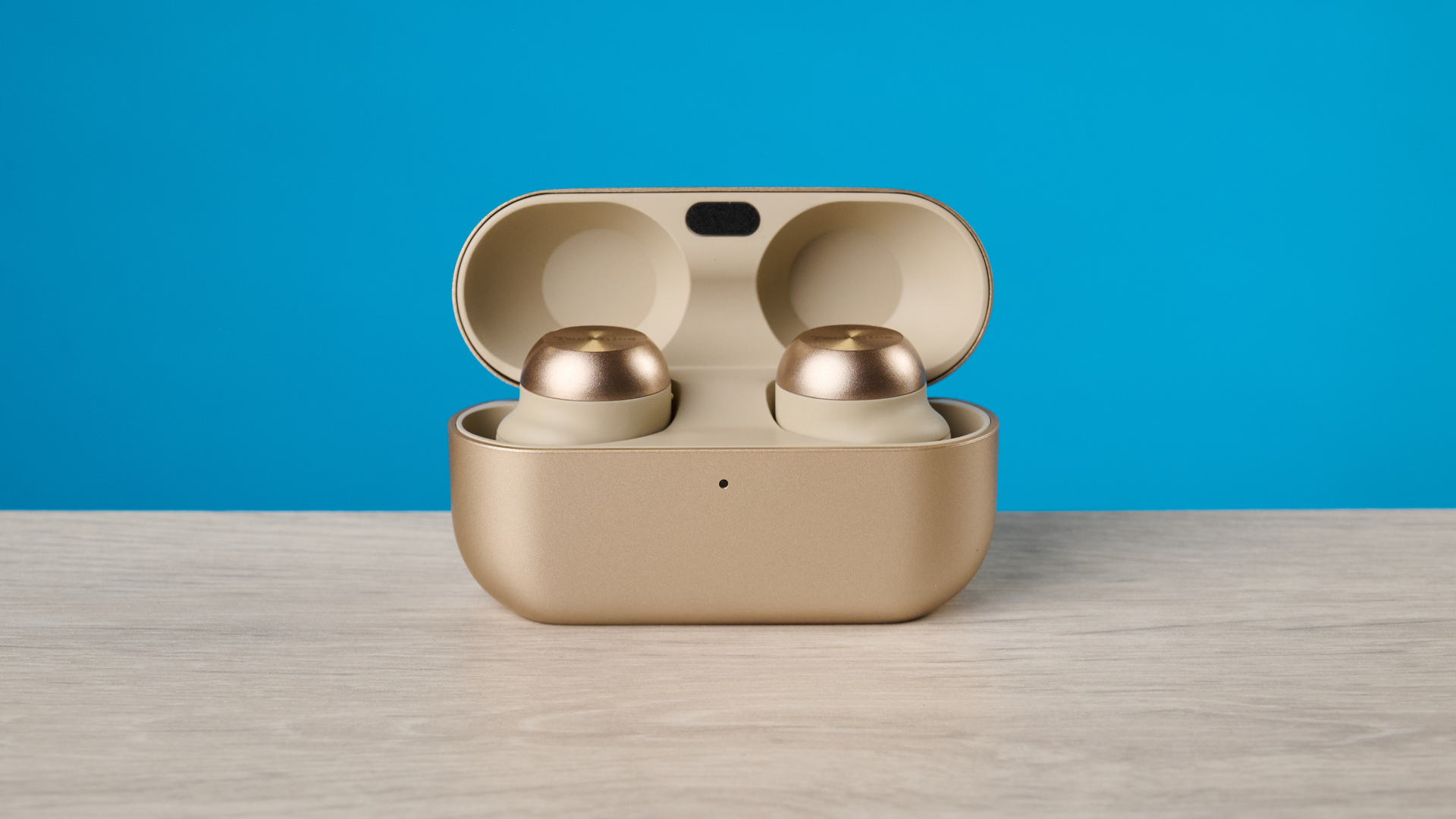 the technics az100 earbuds in champagne photographed against a blue tom's guide background