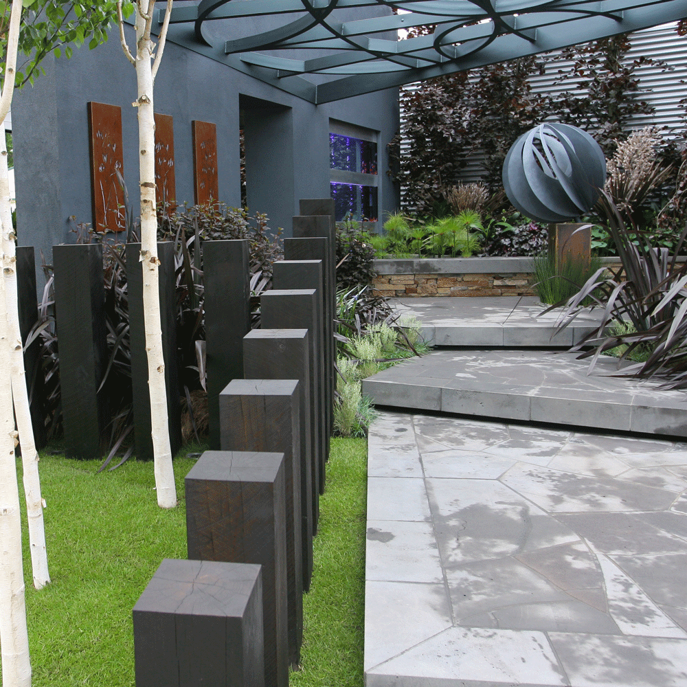 garden area with black wooden plinths and trees