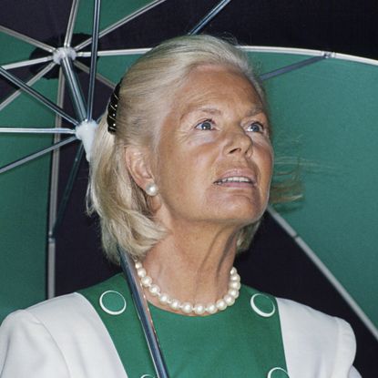 The Duchess of Kent carries a green and black umbrella which coordinates with her white and green dress