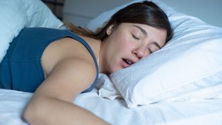 A woman sleeping in bed with her mouth open