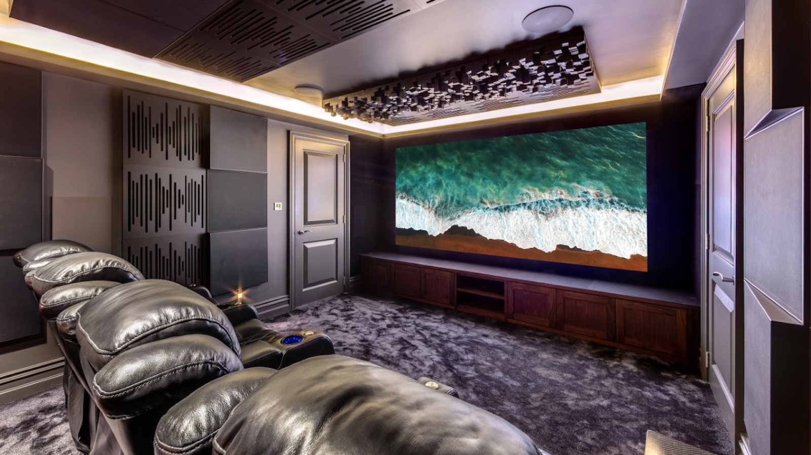 A photo of a custom-installed home cinema room featuring a 4K projector, theatre seating and clever acoustic treatment
