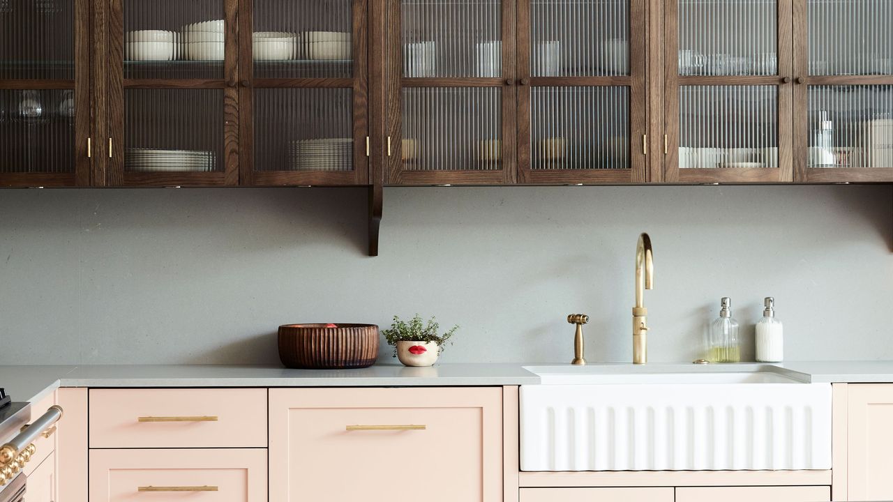 pink cabinets and large butler&#039;s sink with wooden fluted glass upper cabinets